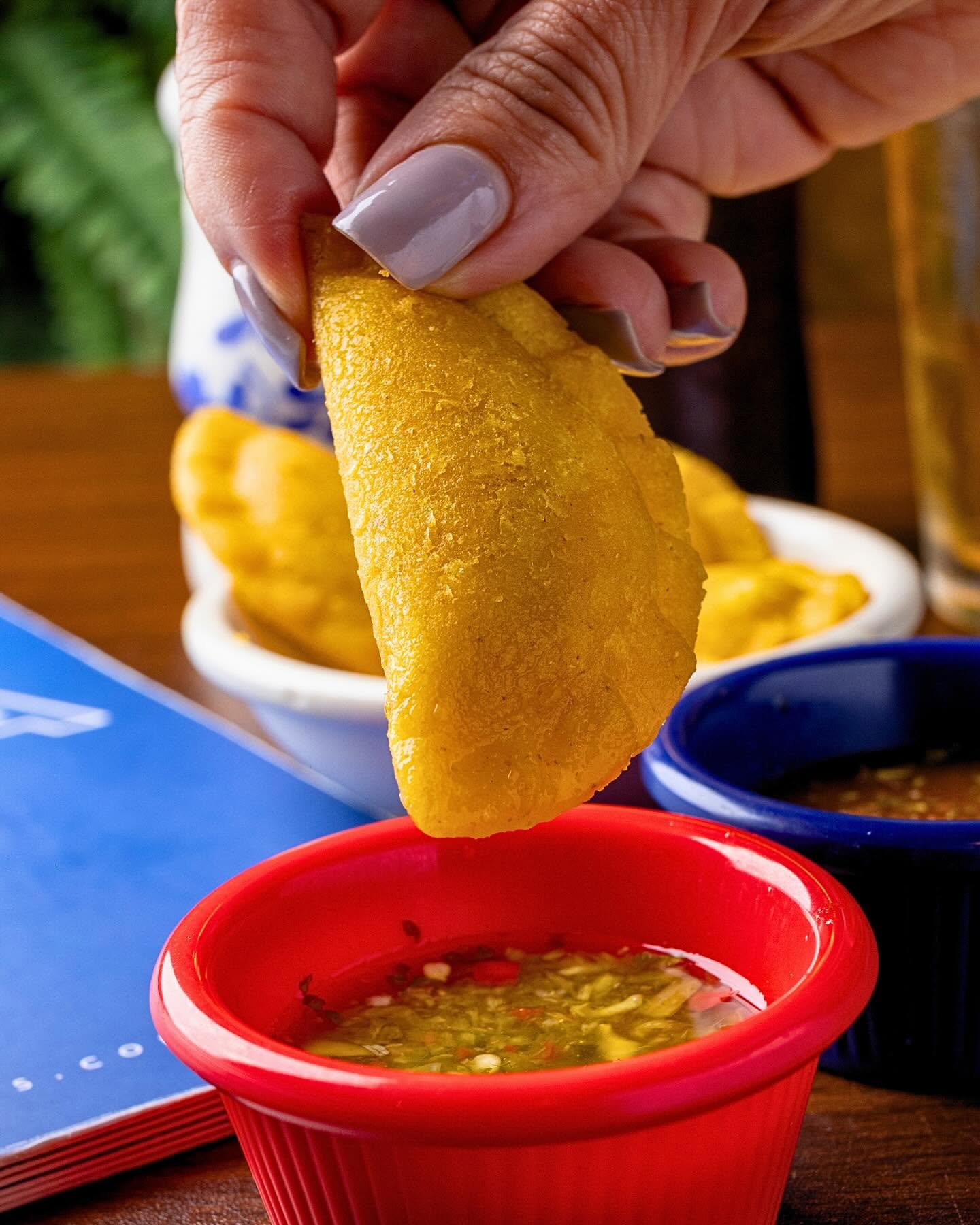 Dipping a Colombian empanada into house ají sauce