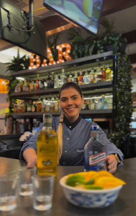 Bartender smiling behind the bar with aguardiente and fresh citrus