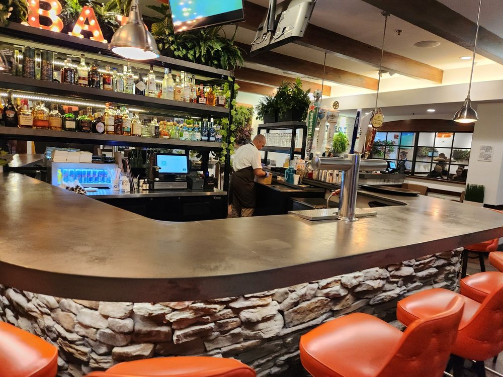 Stone-clad bar with orange stools and a full bottle display