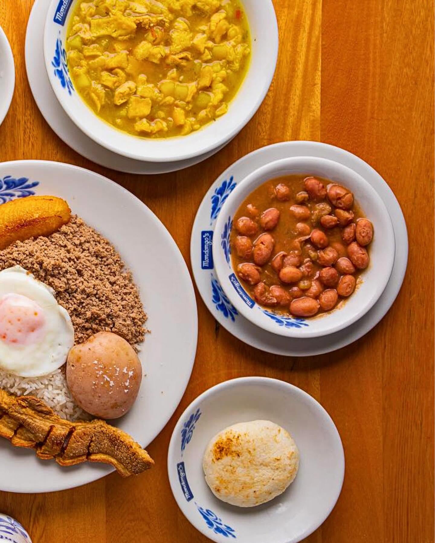 Mondongo soup, red beans and a bandeja plate on a wooden table