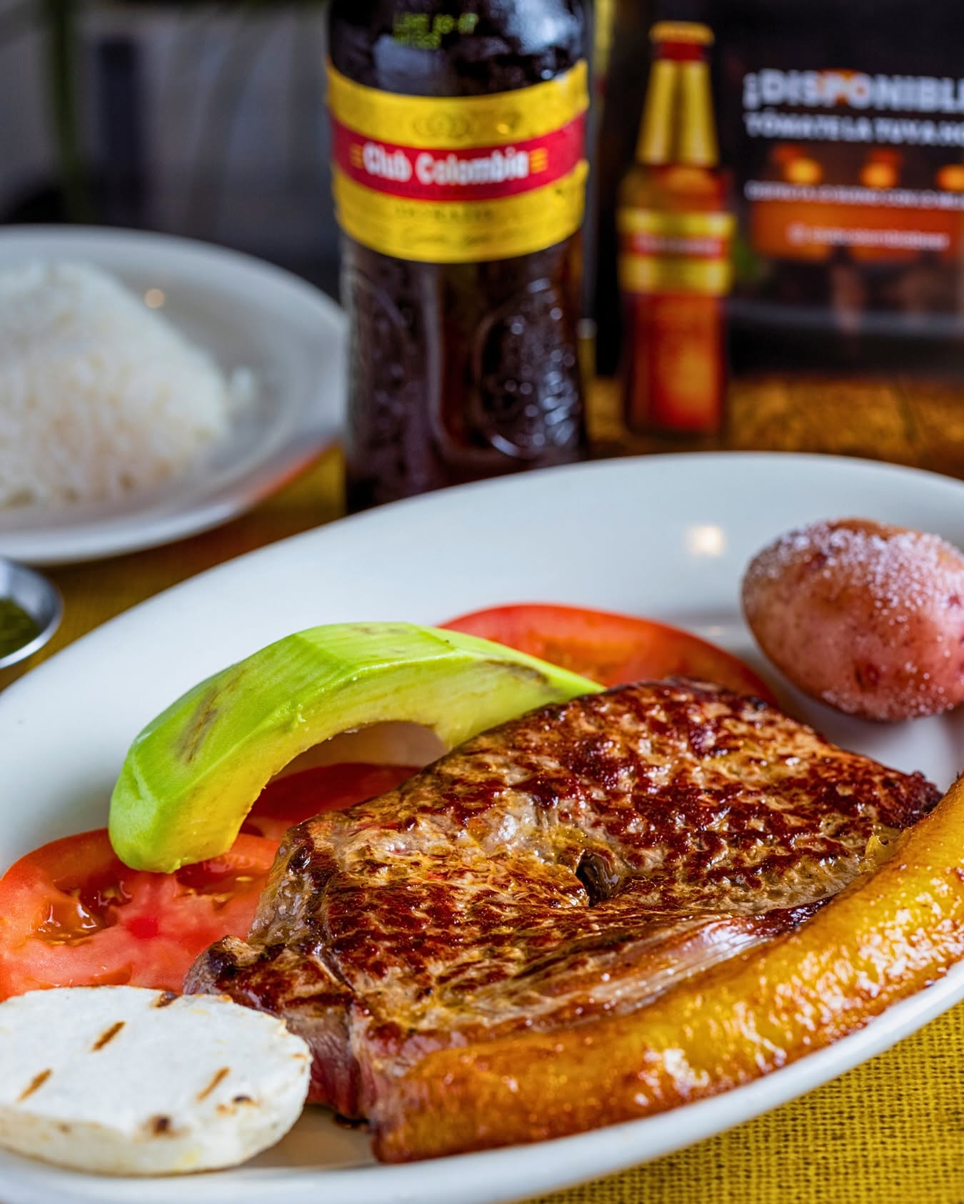 Grilled steak with avocado, tomato, arepa and sweet plantain