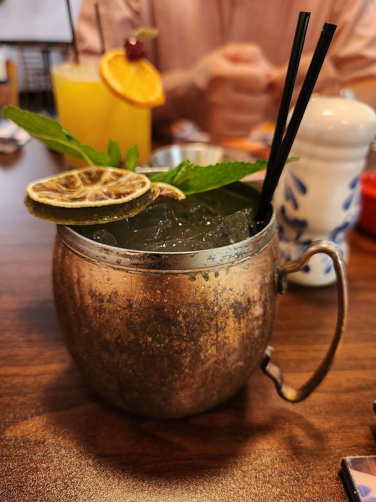 Copper mug cocktail with mint and dried lime at the table