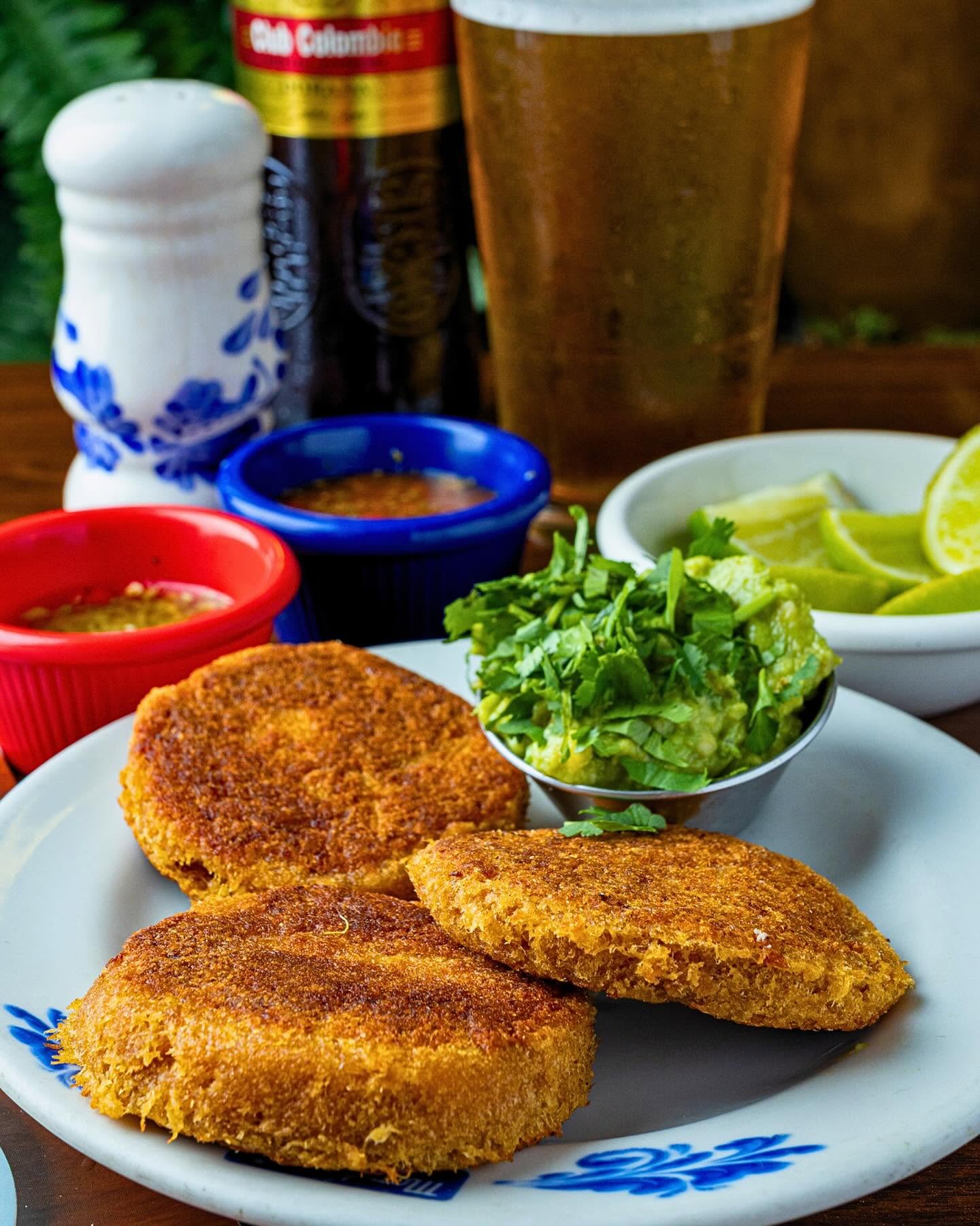 Golden fried carimañolas served with guacamole, lime and ají