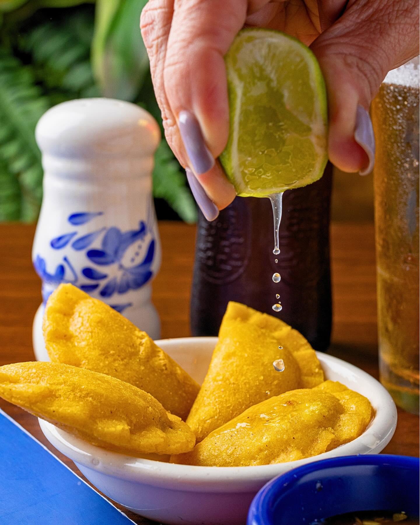 Squeezing fresh lime over a bowl of Colombian empanadas